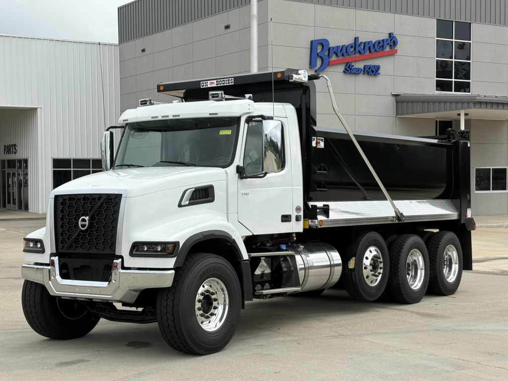 Volvo VHD84F300 dump truck in white with Brackner's dealership building in background.