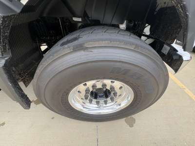 Front wheel and tire of a Volvo VHD truck showing M- توقع? The tire reads M O? The wheel has chrome hub and lug nuts; undercarriage and fender visible.