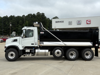 Volvo VHD84F300 dump truck side view showing white cab, black dump body, and tandem rear axles at a service lot.