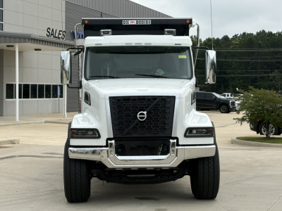 Volvo VHD84F300 dump truck front view showing large black grille, white cab, chrome bumper, and customs bar with lights.