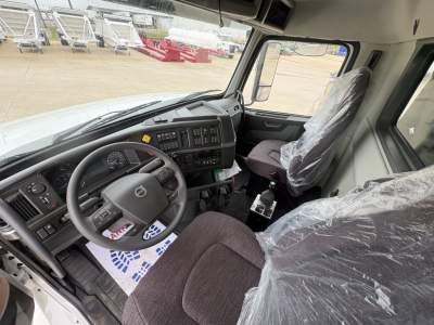 Volvo VHD84F300 truck interior view showing steering wheel, dashboard, driver seat, and protective plastic on seats.