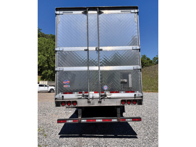 Back view of a silver Utility 3000R trailer with diamond plate doors, dual rear doors, red/white reflective strips, and a bumper with taillights.