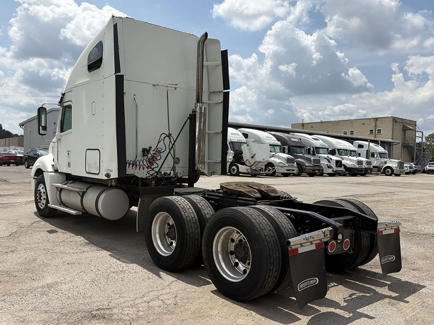 Freightliner CL120 Columbia tractor rear and sleeper cab, dual rear axles, fifth wheel removed, multiple trucks in background.