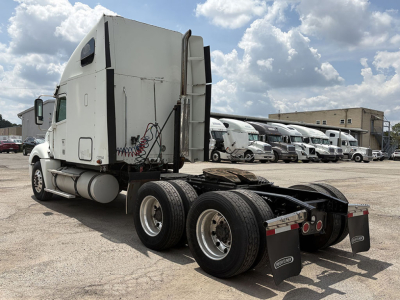Freightliner CL120 Columbia tractor rear and sleeper cab, dual rear axles, fifth wheel removed, multiple trucks in background.
