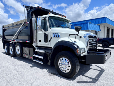 Dump truck 2023 Mack GR84F in-service side view showing cab, front bumper, chrome wheels, dual rear axles, and dump bed.