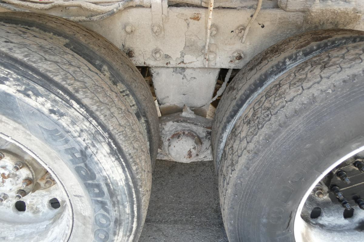 Twin rear wheels and drive axle of a Mack mixer truck showing dual tires and axle housing with suspension and frame members.