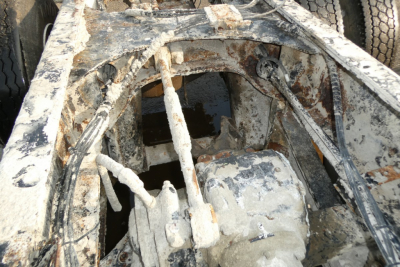 Truck chassis interior showing corroded frame and mechanical components of a Mack mixer truck, rust and grime on metal surfaces.