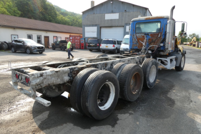 Mack CTP713 mixer truck chassis shown from rear/side with triple rear axles and worn frame.
