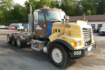 Truck side view showing a Mack CTP713 mixer chassis with yellow cab and blue sleeper, front numbered 568, multiple wheels, in-service condition.
