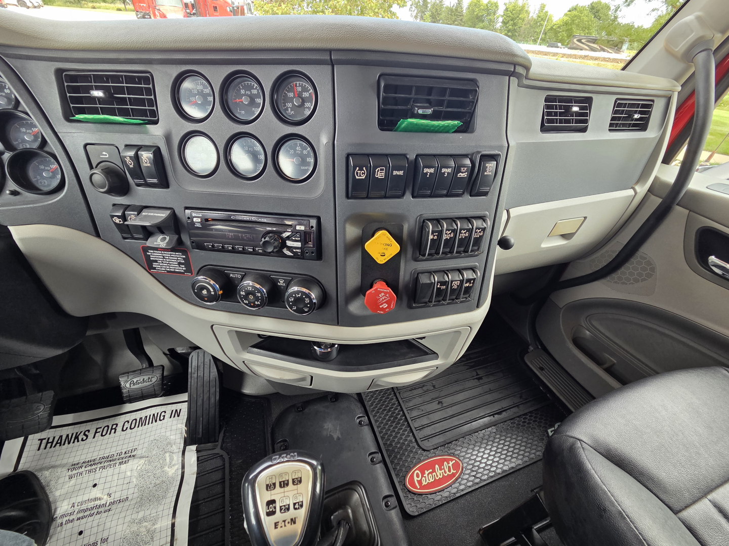 Peterbilt 567 truck interior dash showing gauges and controls; fuel, warning and auxiliary switches; Peterbilt branded floor mat.