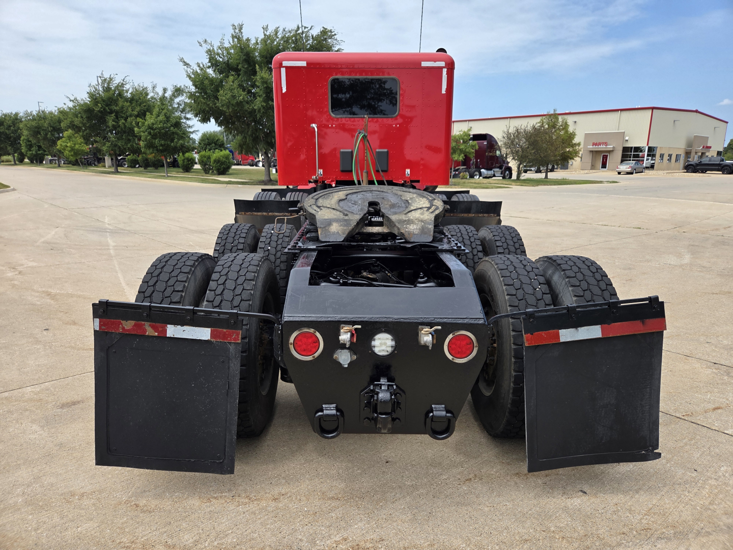 Peterbilt 567 tractor rear view showing fifth wheel, dual rear axles, and mudflaps.
