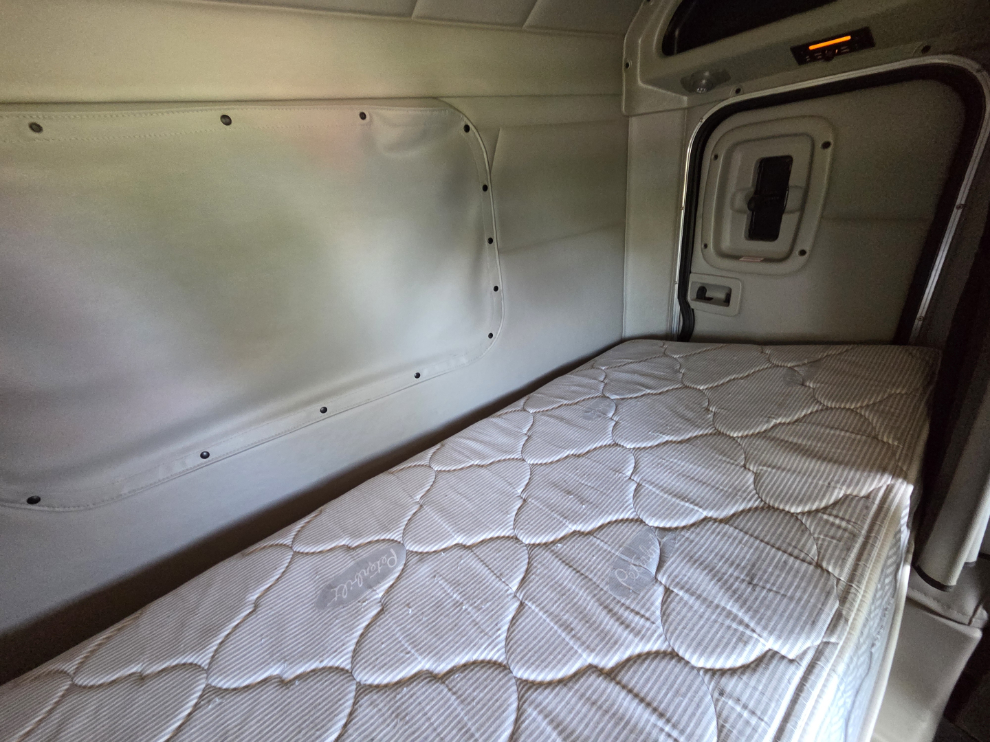 Peterbilt 567 truck sleeper cabin interior with a single mattress and side panel; no visible labels or text.