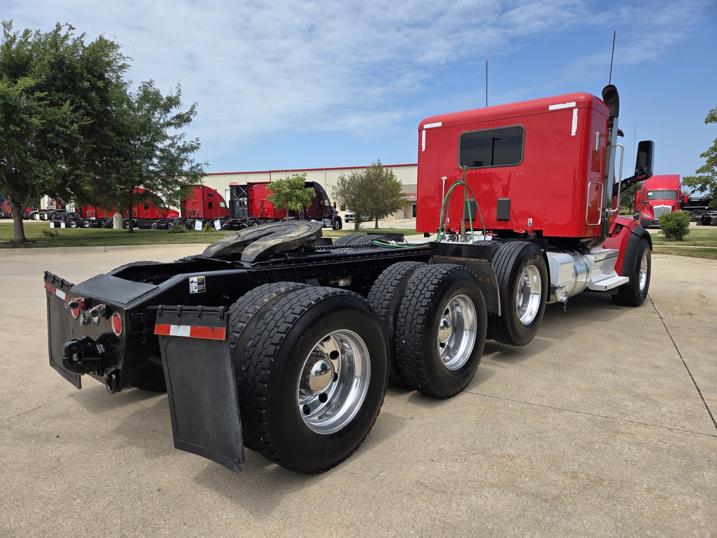 Peterbilt 567 truck chassis and cab in red, side view showing triple rear axles and fifth wheel area.