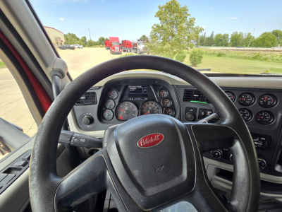 Peterbilt truck driver cockpit view showing steering wheel and instrument cluster.
