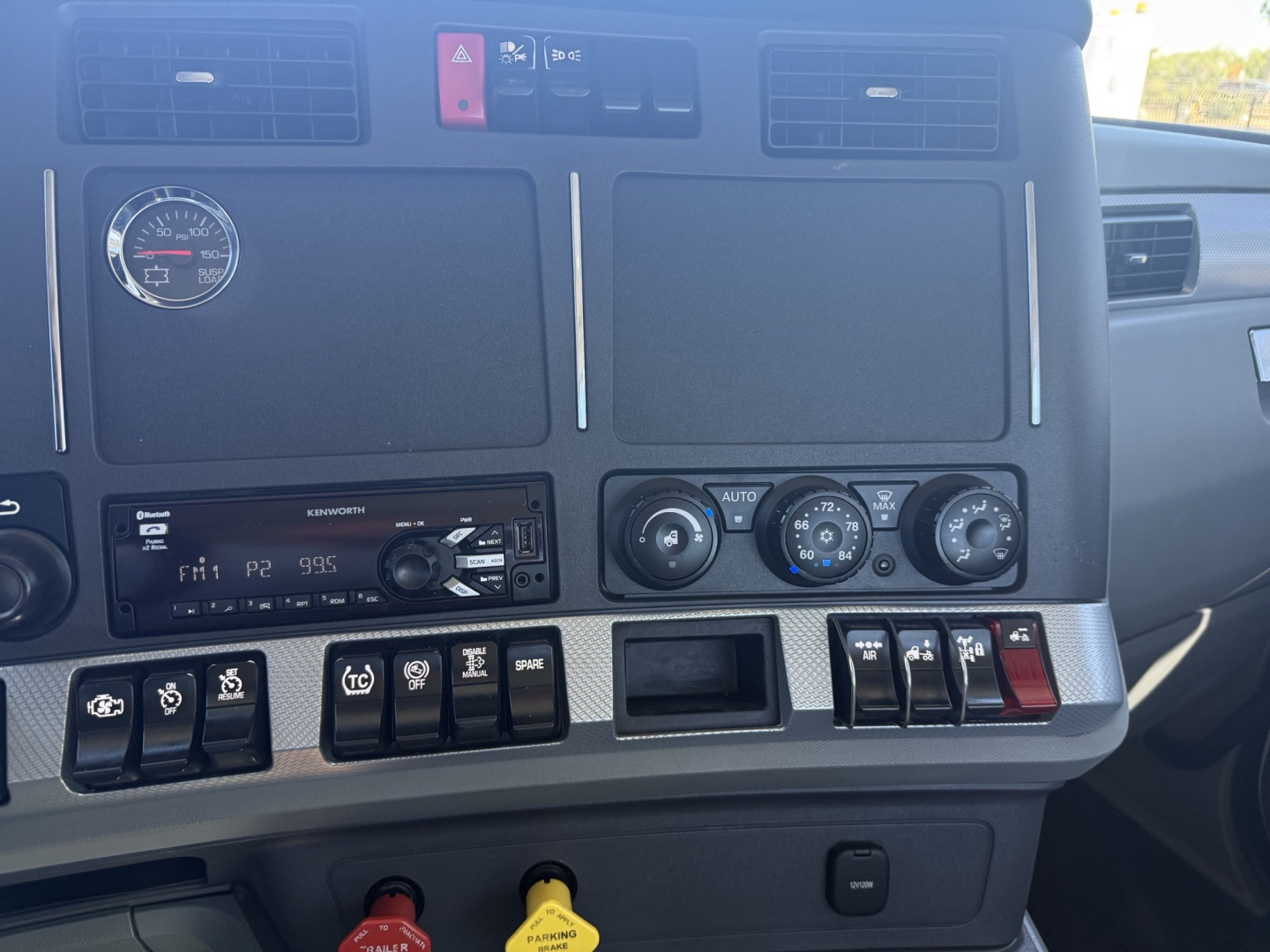 Kenworth T680 dashboard view showing climate controls, radio, and various switches and gauges.