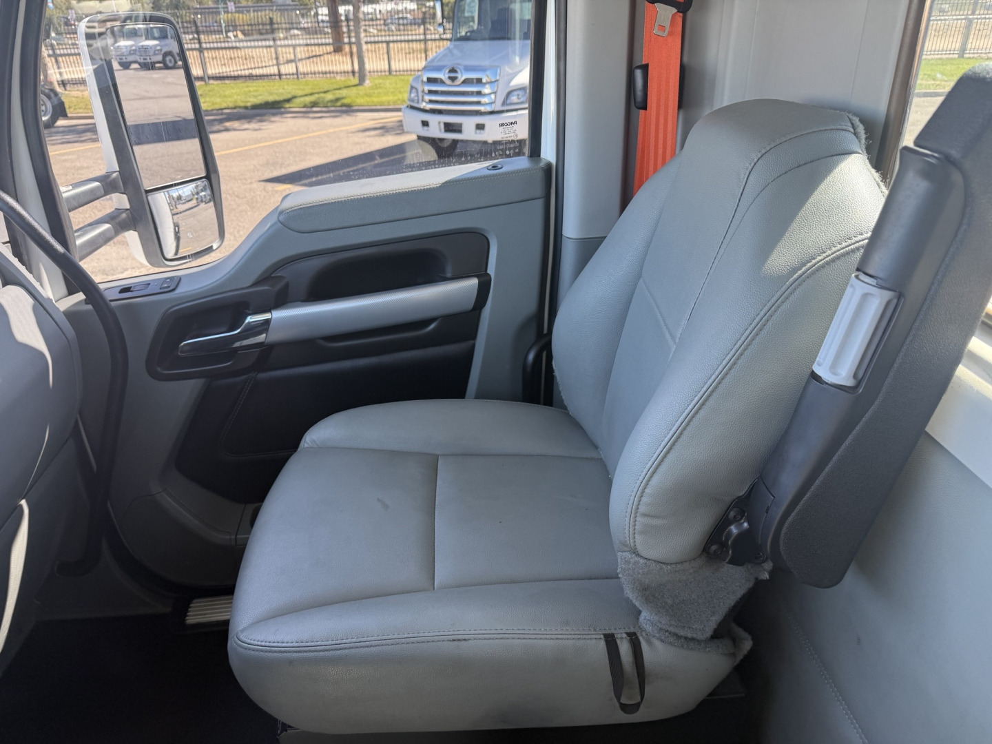 Kenworth T680 cab interior showing front passenger seat and dashboard area in a daytime setting.