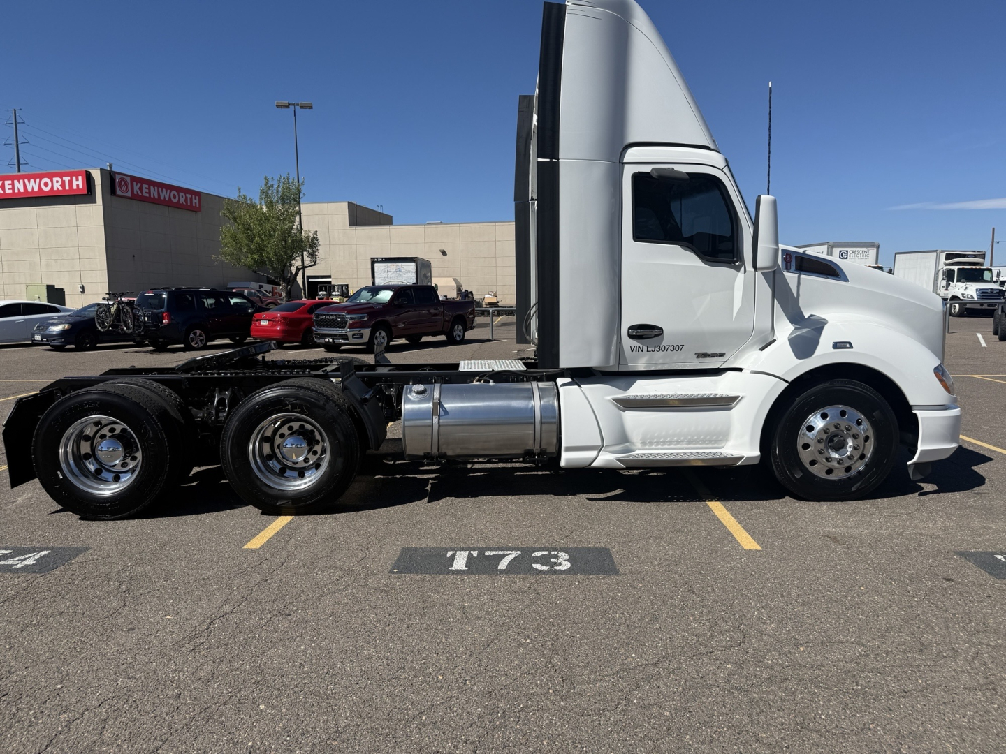 Kenworth T680 tractor side view showing cab and dual rear axles with chrome fuel tanks and wheels.