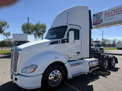 Kenworth T680 daycab truck in white, side view showing front grille, aerodynamic sleeper cab, dual rear axles, and fuel tanks.