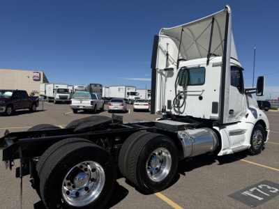 KENWORTH T680 truck with a raised sleeper cab in a parking lot; side view shows rear tractor frame and dual rear axles; chrome fuel tanks and wheels visible.