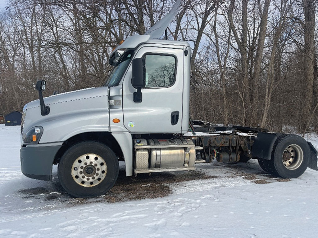 Cab over engine Freightliner Cascadia125 tractor in snow, side view showing fuel tanks and chassis, no trailer attached.