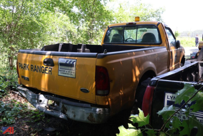 Ford F-250 Super Duty pickup in yellow Park Ranger livery with damaged rear bumper and bed area, outdoor setting