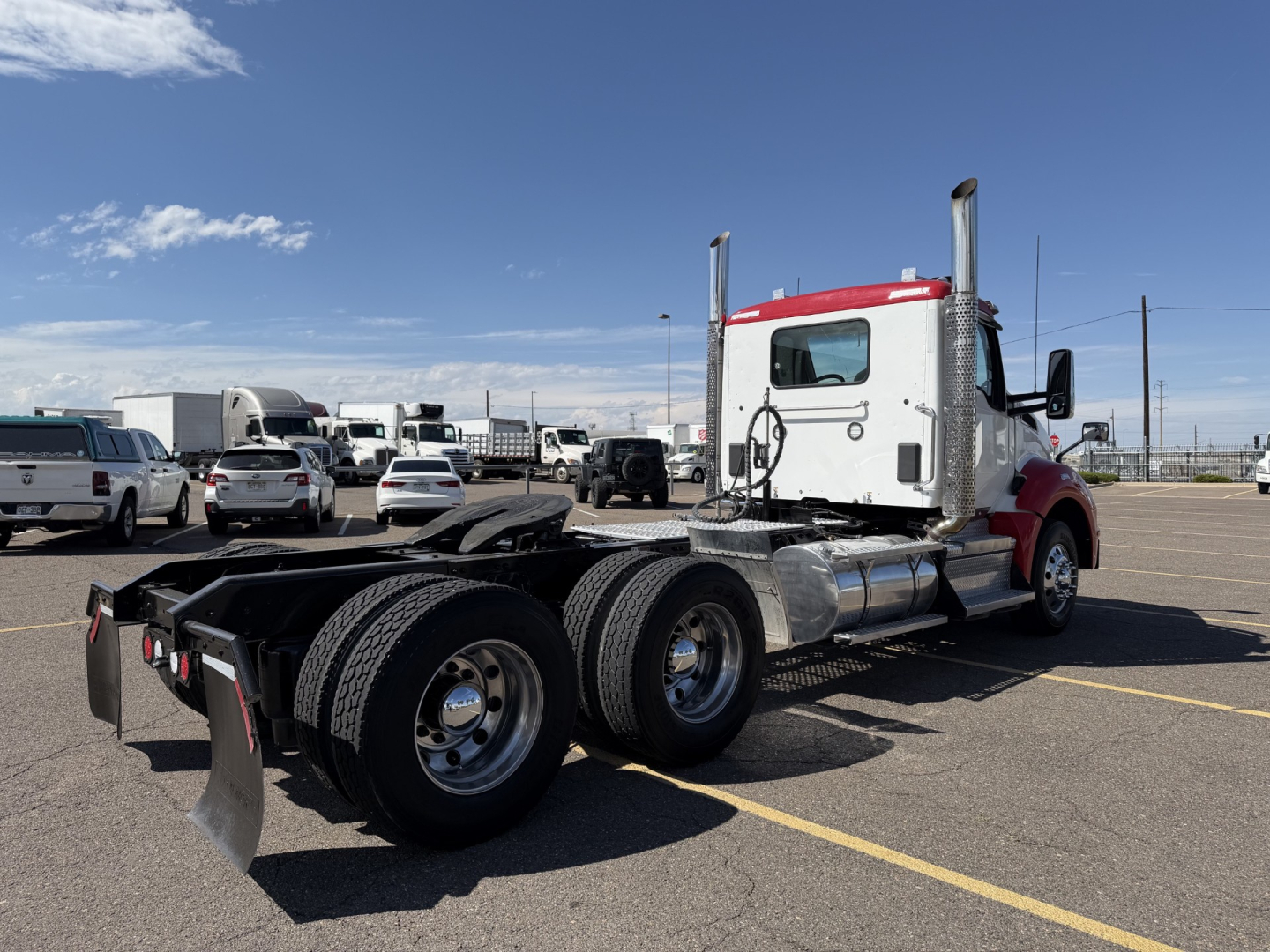 Kenworth T880 conventional daycab truck side/rear view showing dual rear axles and chassis with fuel tanks and exhaust stacks.