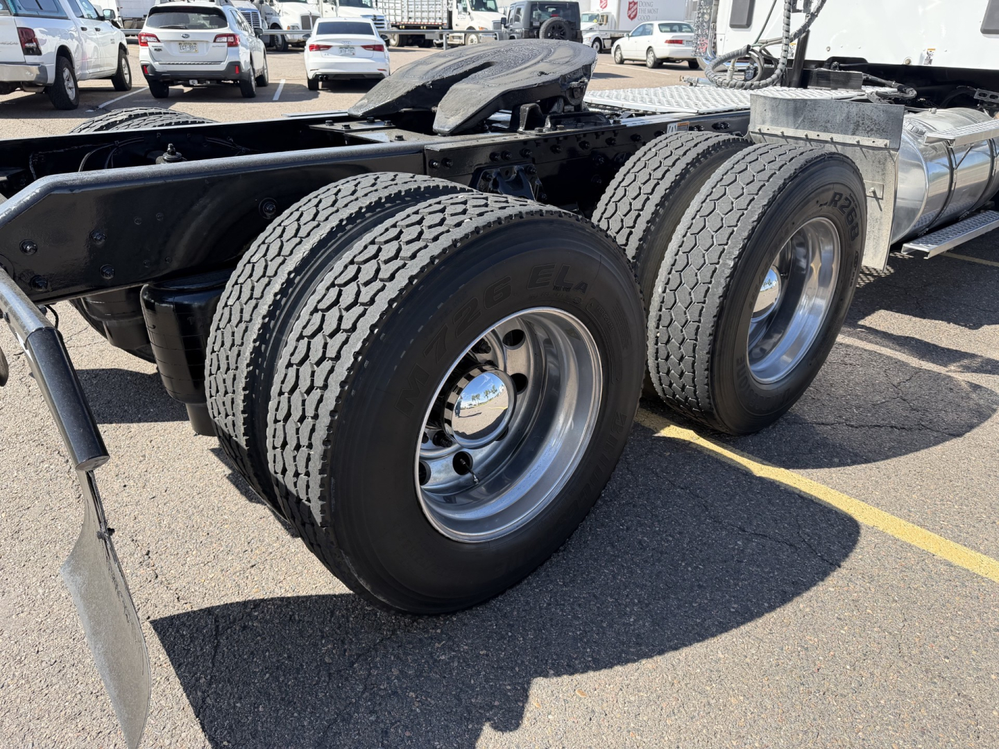 Kenworth T880 chassis with dual rear axles and large dual tires, wheel rims visible, truck in a lot.