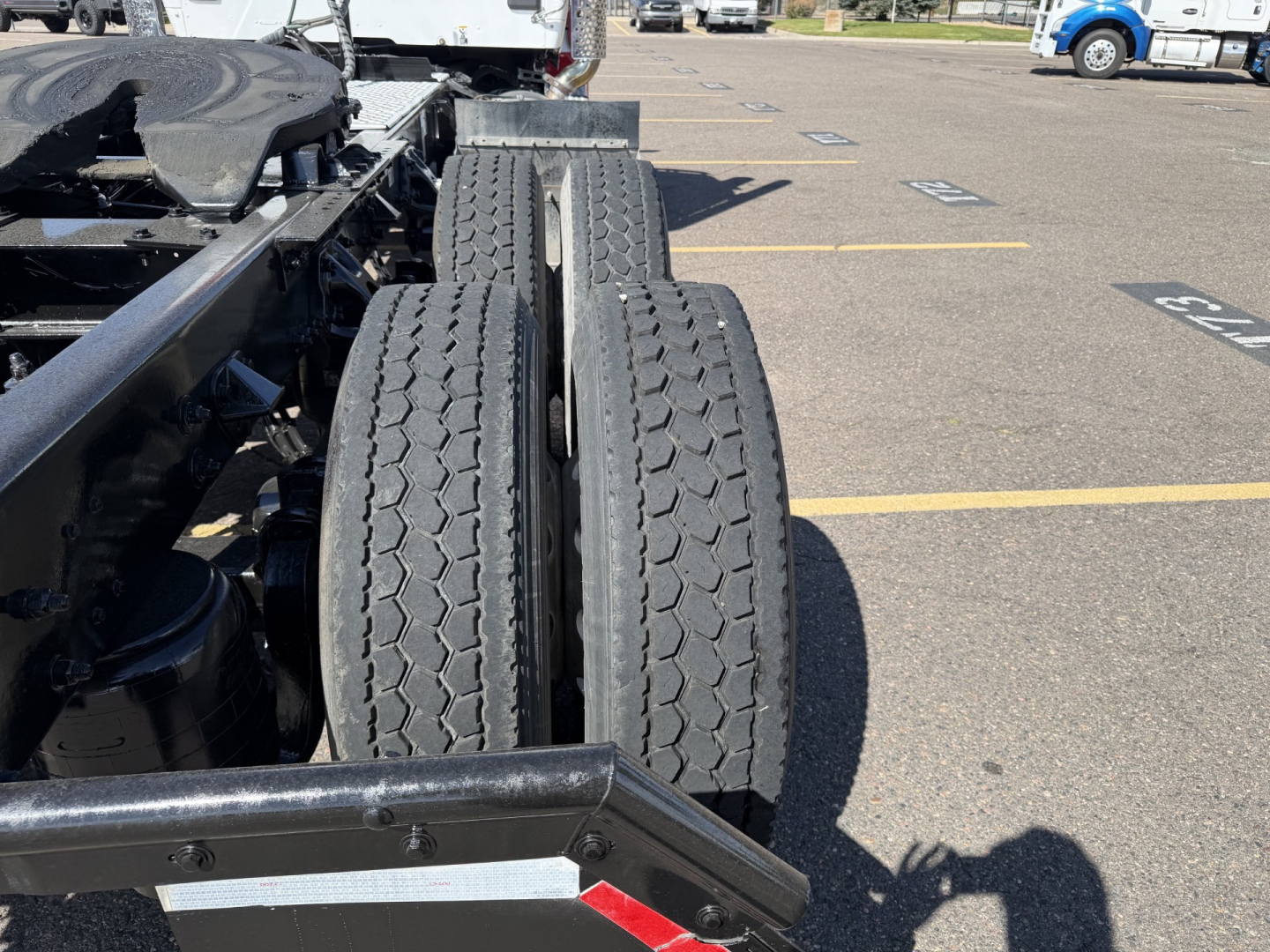 Kenworth T880 truck chassis showing dual rear wheels and tire tread in a parking lot.