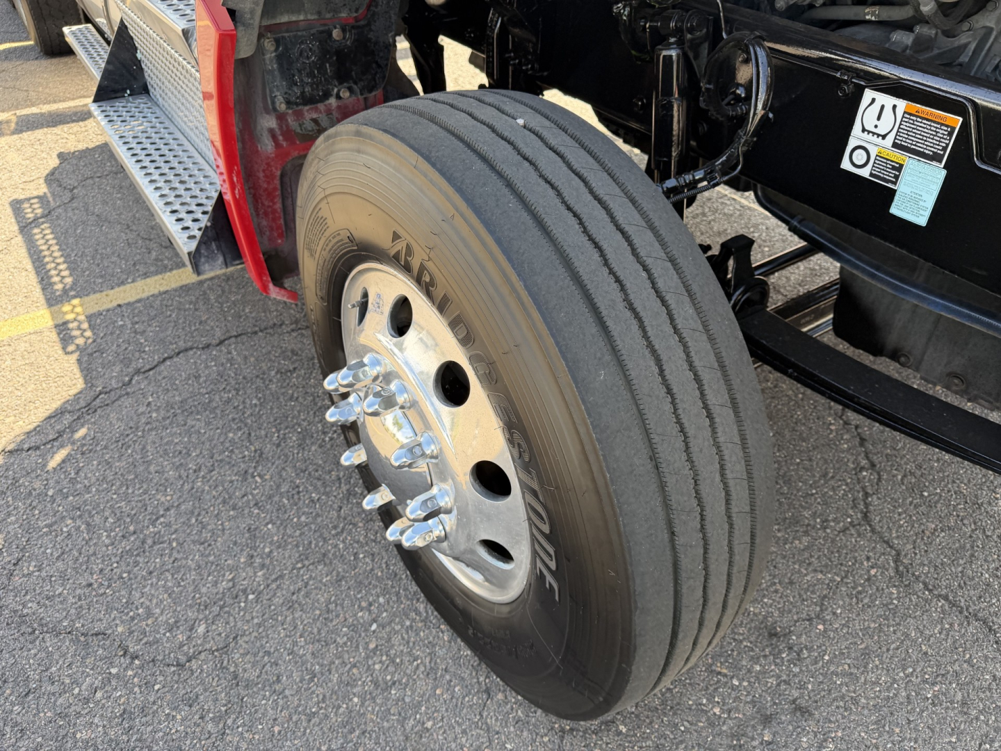 Kenworth T880 front wheel and tire on a daycab, showing front axle and dual tread tire with hub and lug nuts.