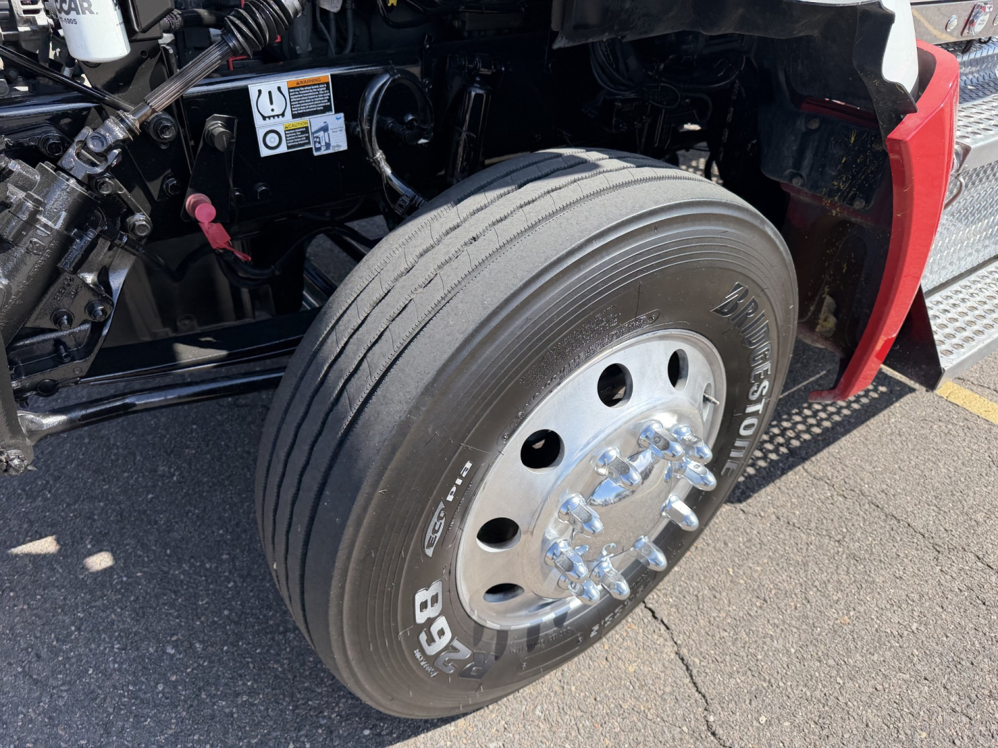 Kenworth T880 front wheel and suspension area with tire and wheel studs visible.