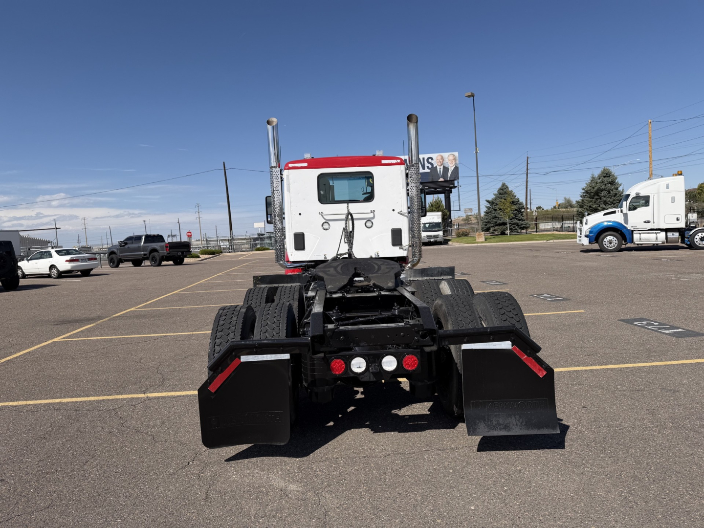 Kenworth T880 tractor rear view showing fifth wheel and mud flaps in a dealership lot