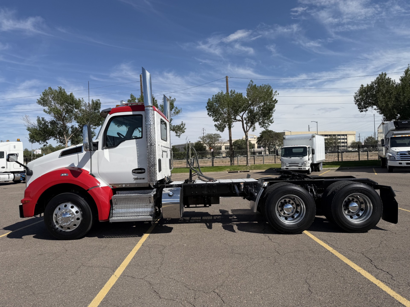 Kenworth T880 conventional daycab tractor in a parking lot, side view showing chassis, cab, fuel tanks, and dual rear axles.
