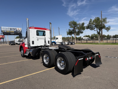 Kenworth T880 conventional daycab with dual rear axles and fifth-wheel, side view showing chassis and rear tires.