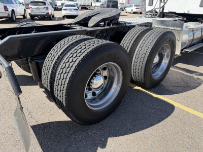 Kenworth T880 chassis rear dual rear axles showing dual tires and fuel tank in a parking lot.