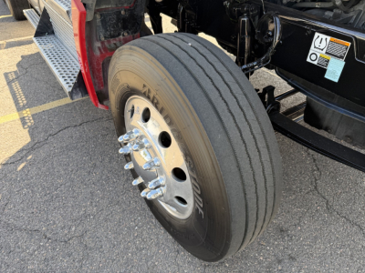 Kenworth T880 front wheel well showing steering axle dual tires and wheel with lug nuts and hub,  candidate engine-free bay area visible.