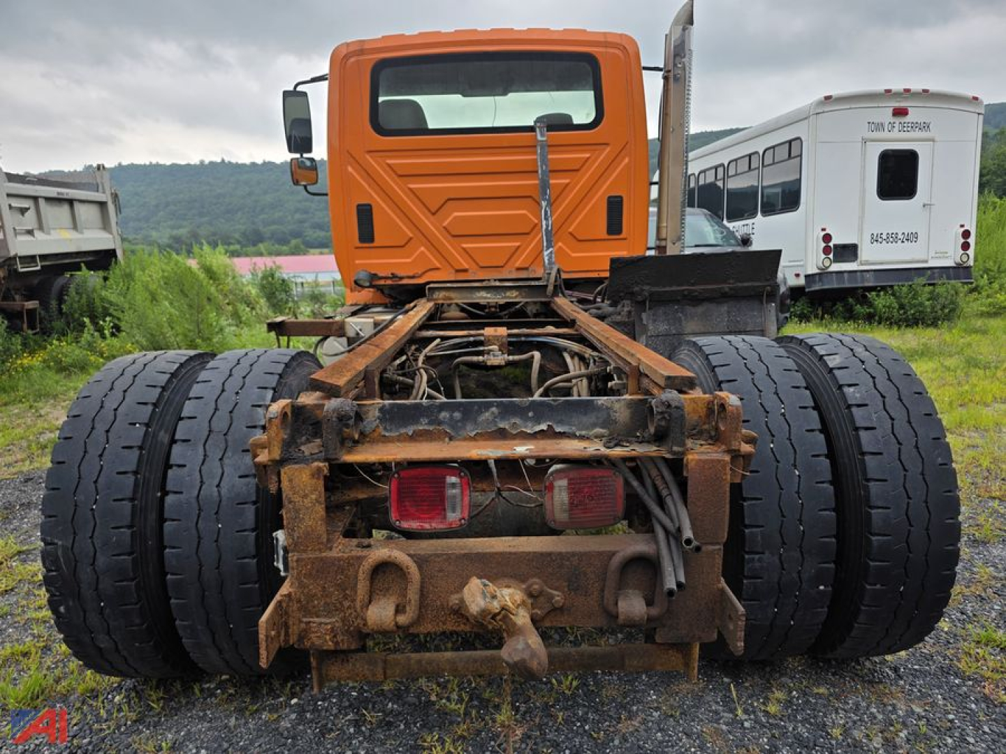 Cab and chassis rear view of a 2003 International Workstar 7500 showing dual rear axles and hitch assembly with rusted frame and taillights.