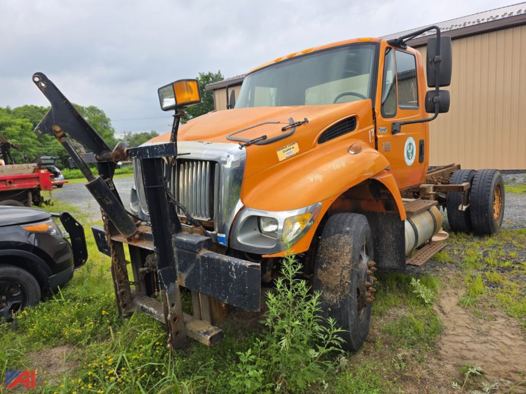 Orange International WorkStar 7500 cab and chassis truck with front mount snow plow attachment and dual rear wheels; visible text and labels on cab and bumper.