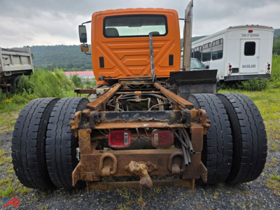 Cab and chassis rear view of a 2003 International Workstar 7500 showing dual rear axles and hitch assembly with rusted frame and taillights.