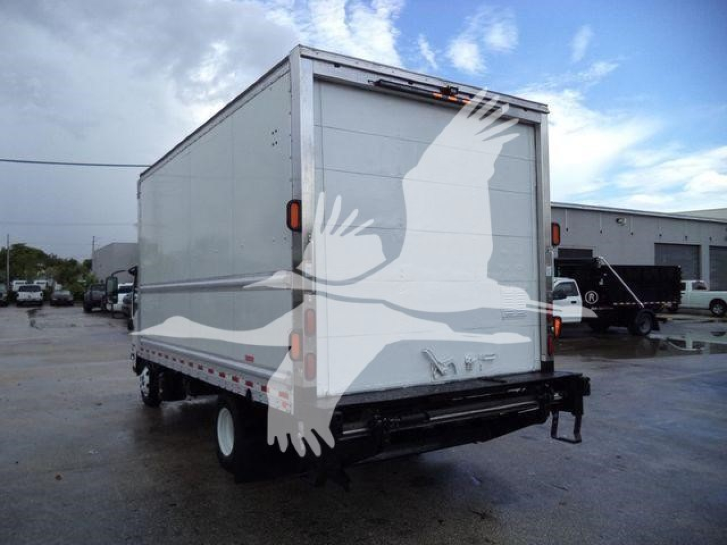 Isuzu NPR HD box truck rear view showing large white cargo box with reflective tail lights and bumper; stock number T05048FM listed.