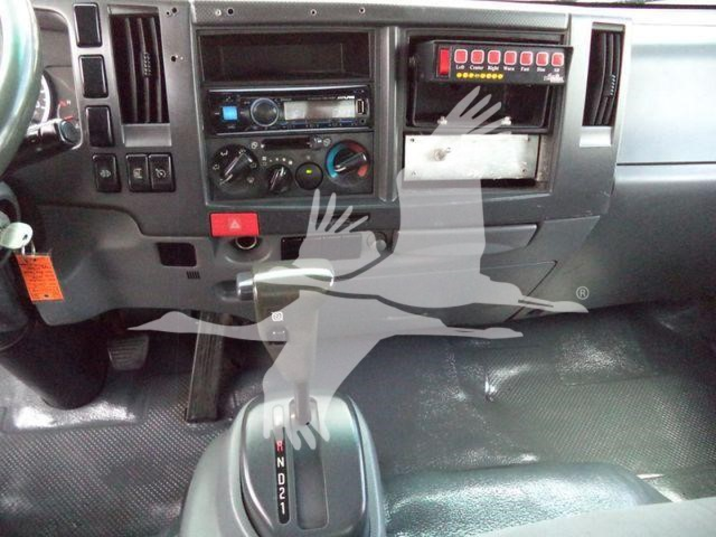 Isuzu NPR-HD truck dashboard with gear selector, climate controls, and switch panel visible.