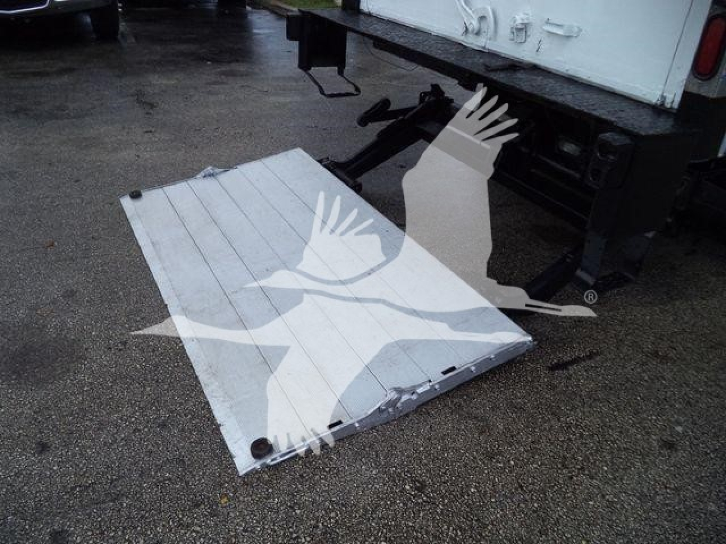 Isuzu NPR-HD box truck rear showing a white aluminum tailgate down on the ground near the back of the truck.
