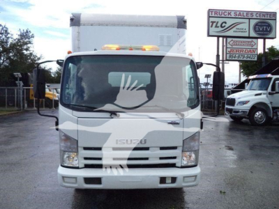 Isuzu NPR-HD truck front view in a used inventory lot with dealership signs in background.