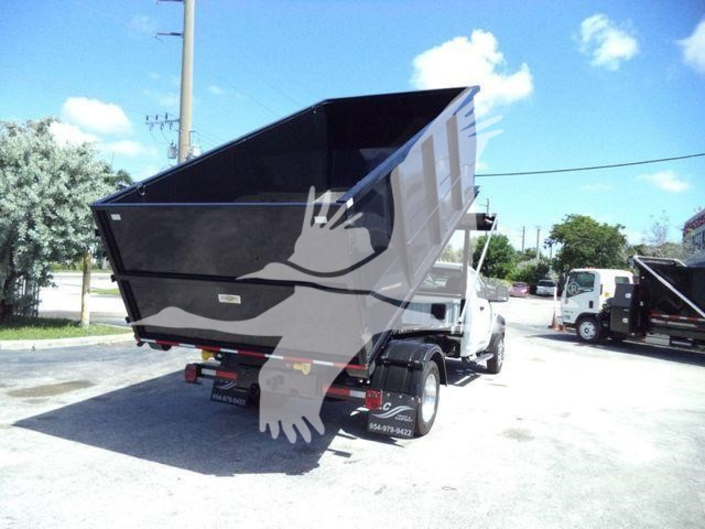 Ram 5500 dump truck in-service showing rear dump bed raised, black dump body, white cab, stock number visible in yard.