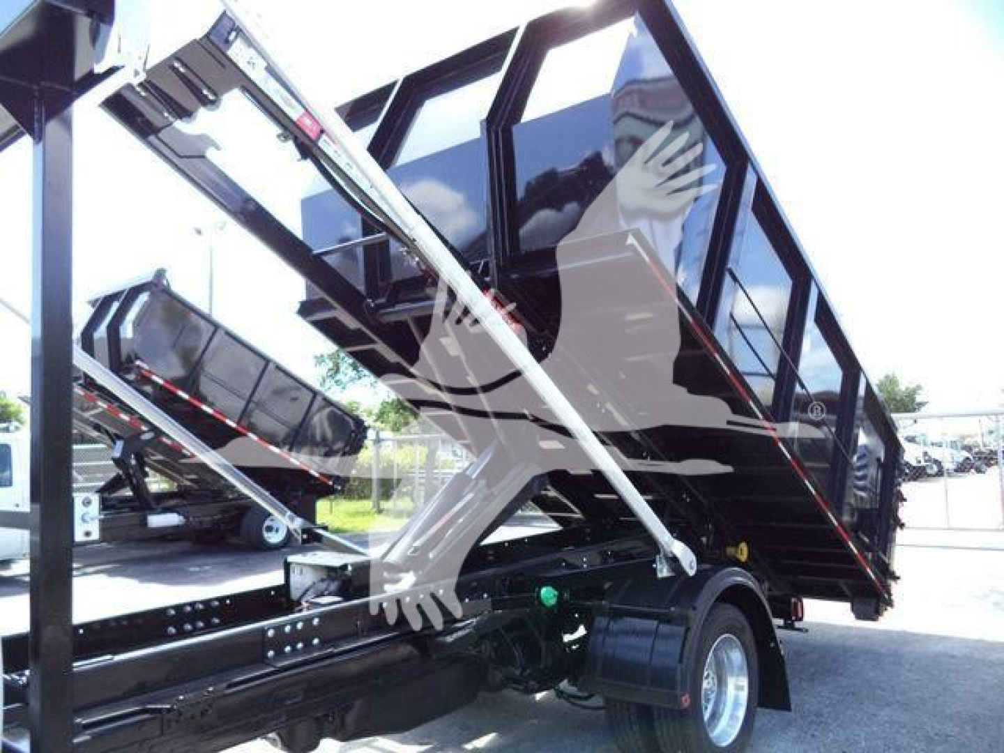 Ram 5500 dump bed / roll-off truck chassis with hydraulic arms and black cab visible.