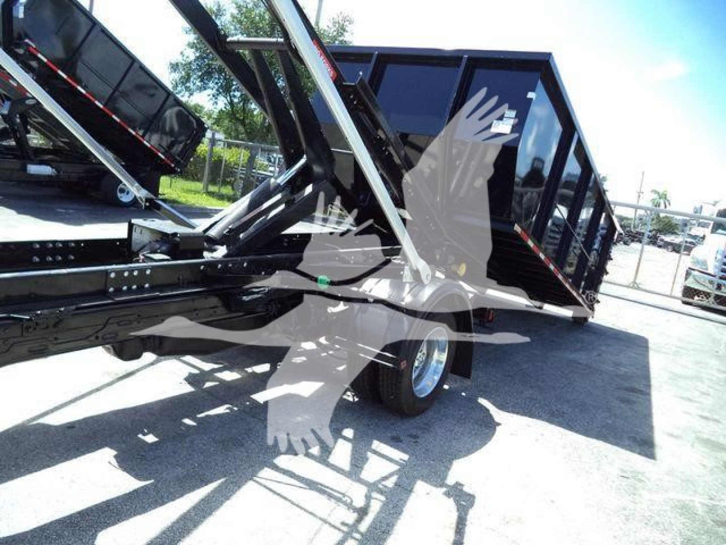 Truck bed with hydraulic dump/roll-off mechanism and rear container in view; no legible brands or model text visible on components.