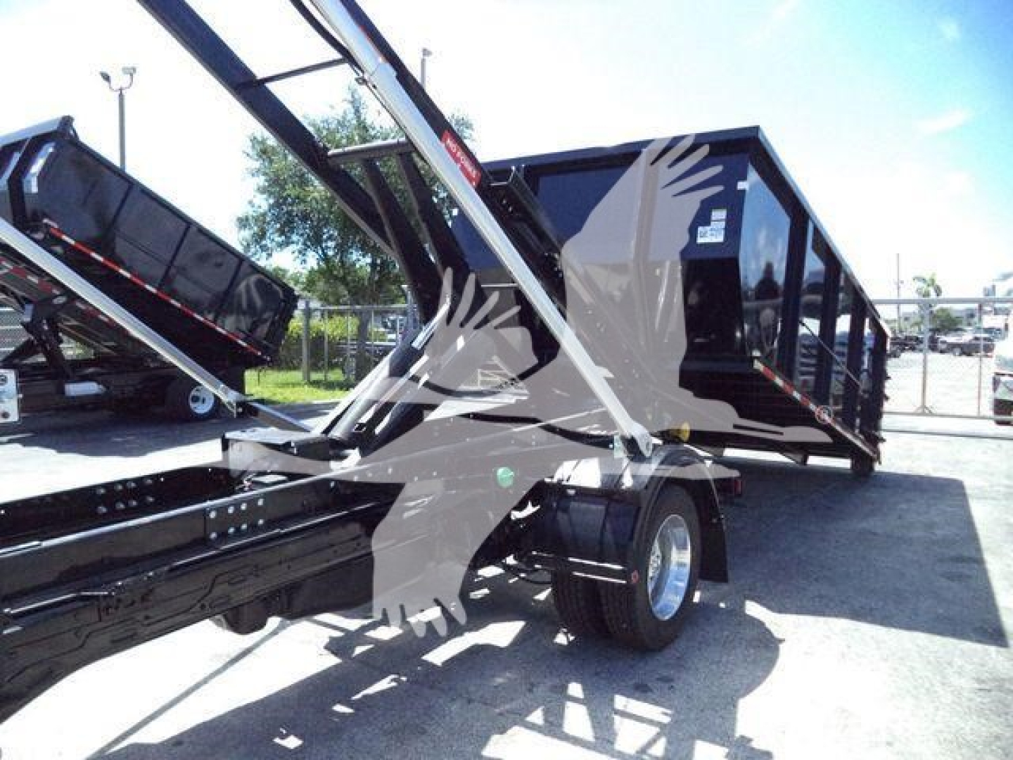 Ram 5500 dump truck with roll-off hoist structure and black cab, visible wheels and storage container.