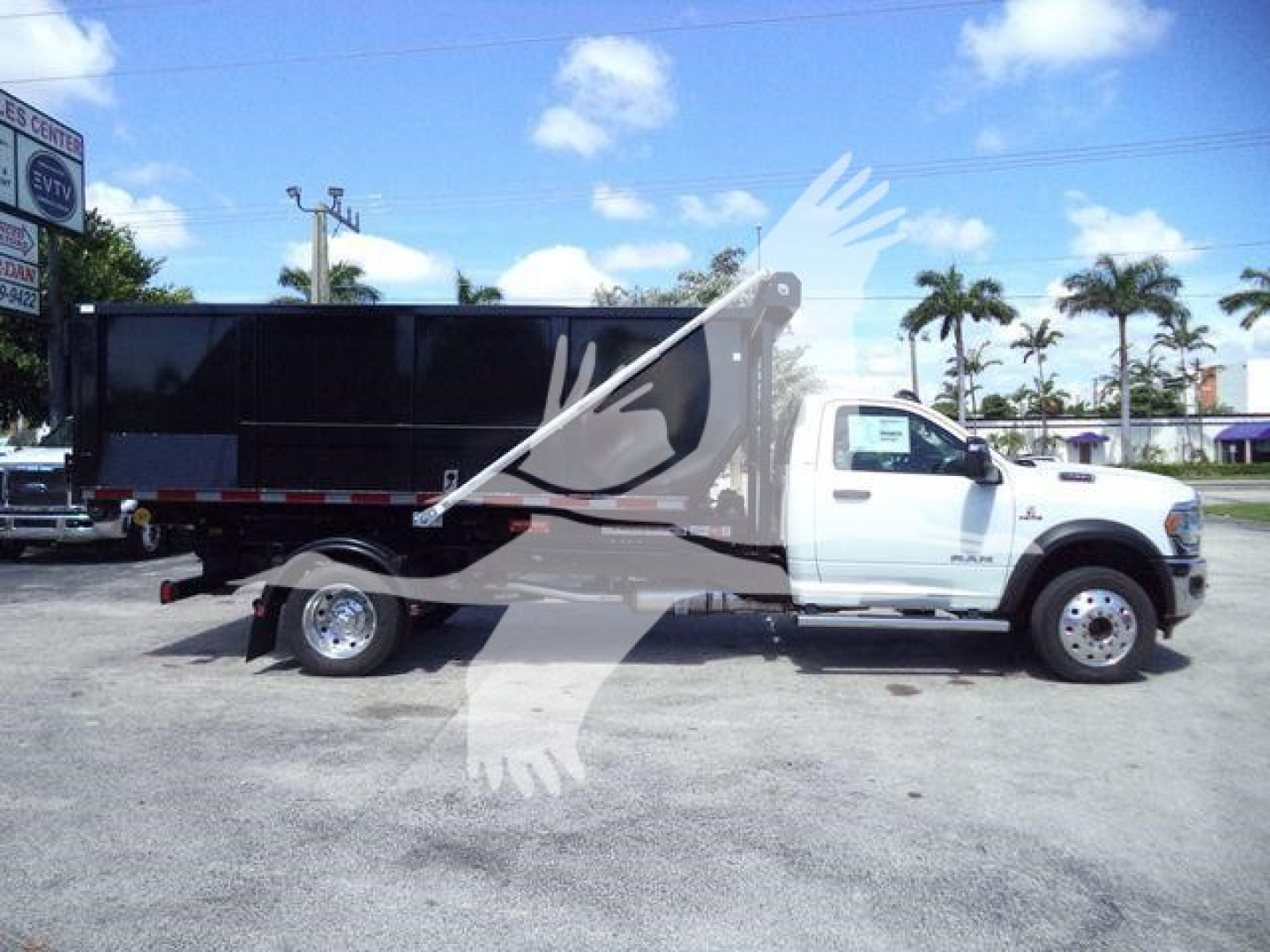 Ram 5500 dump truck in service view showing white cab and black dump body with extended wheelbase.