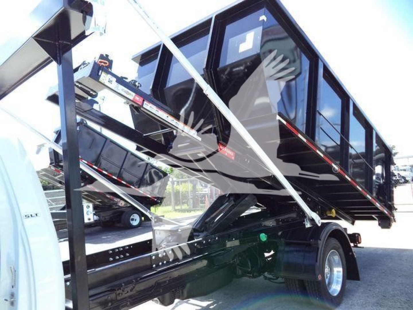 Ram 5500 HD SLT dump truck side view showing raised dumping bed and hydraulic lift under a black exterior