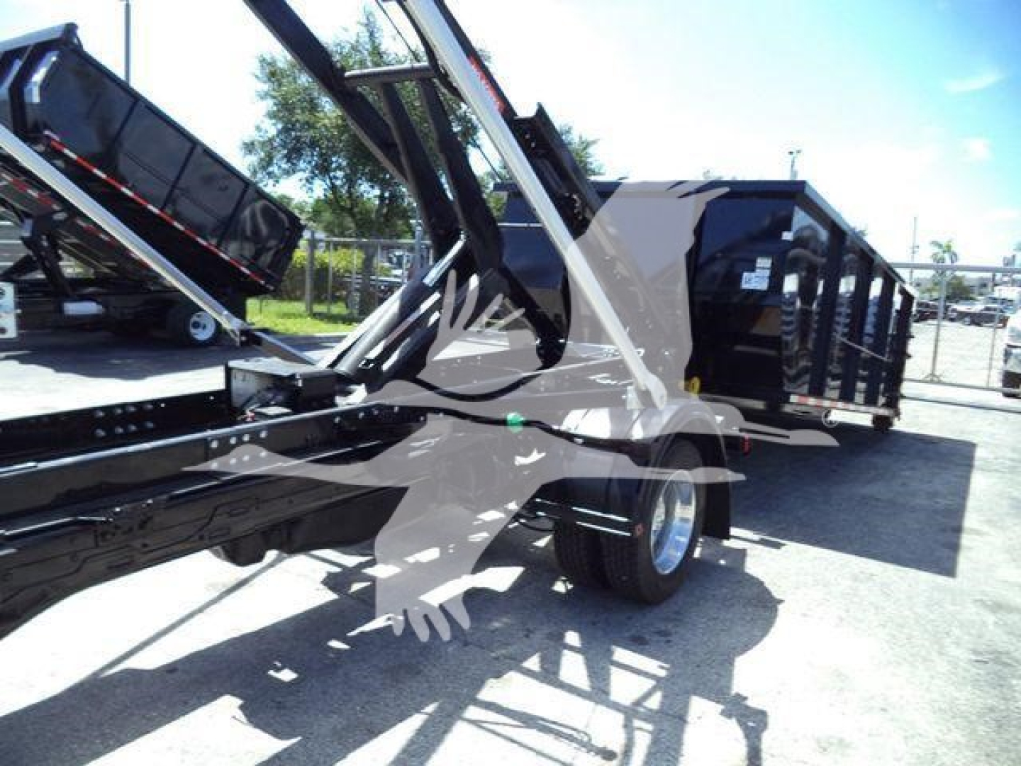 Ram 5500 HD SLT roll-off truck body and hydraulic hoist in view showing equipment trailer with black paint and metal framework.