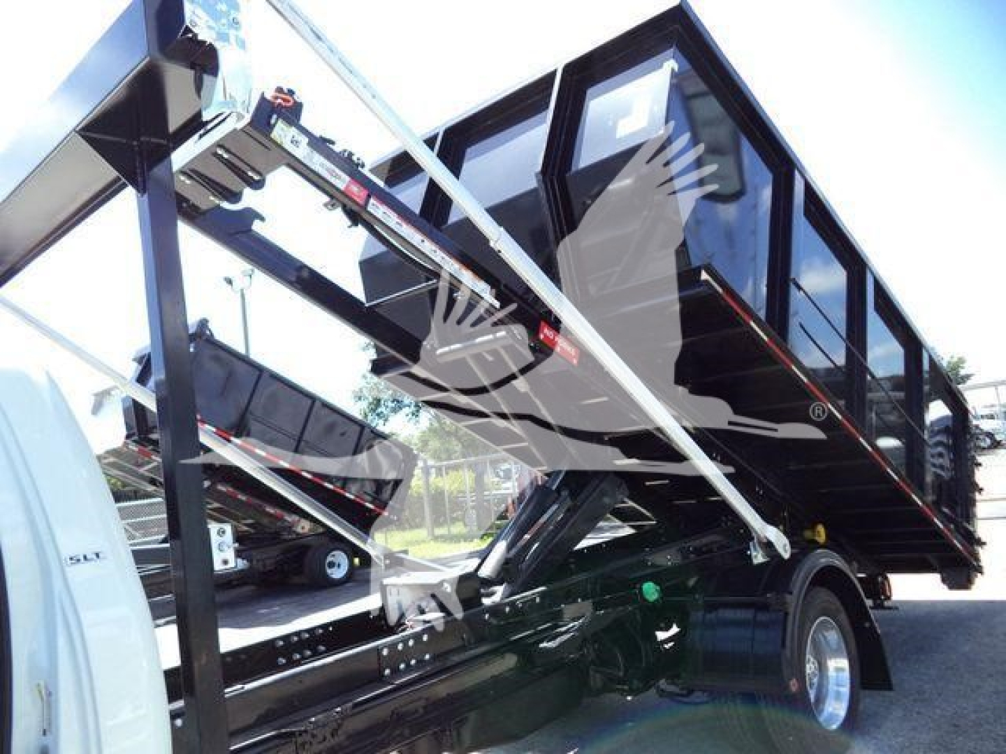 RAM 5500 HD SLT bucket truck/rolloff body with hydraulic lifting mechanism and dump bed, side view showing black truck bed and trailer hitch, 2024 model year